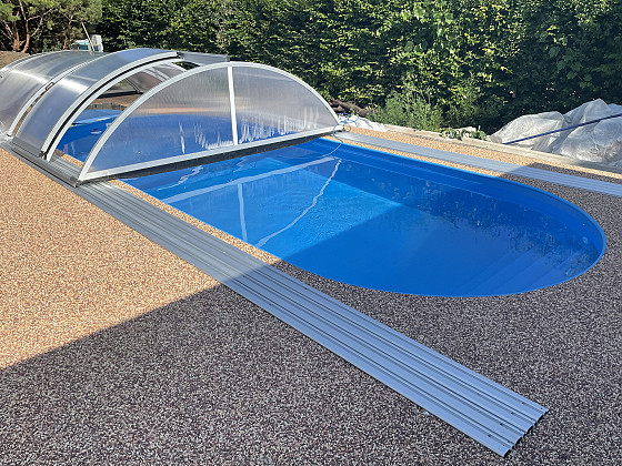 Modrý oválný bazén se zastřešením praktik