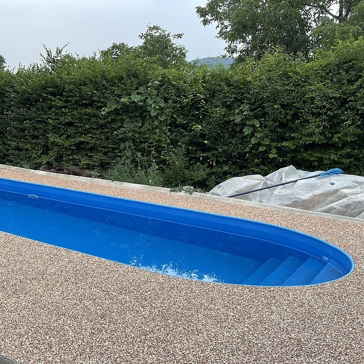 Oválný bazén v modré barvě, schodiště přes celou šíři